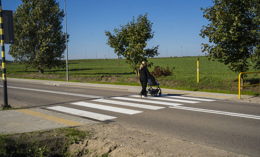 Chodnik i przejście dla pieszych, na przejściu kobieta z wózkiem.